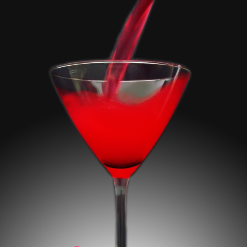 A red liquid being poured into a martini glass, with red roses placed at the bottom of the glass on a gradient gray background.