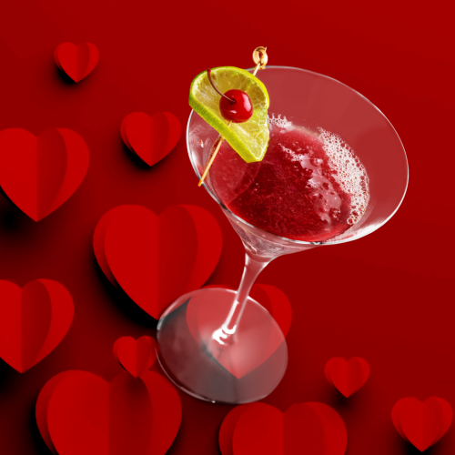 A red cocktail in a martini glass with a lime and cherry garnish, set against a background of red hearts.