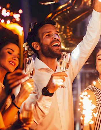 A group of people celebrating with sparklers and champagne at a festive event, smiling and enjoying the moment.