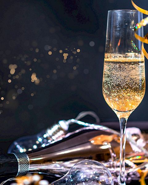Two champagne flutes clink with ribbons and confetti in a festive celebration. Cheers to a sparkling night.